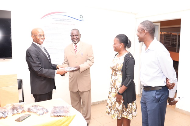 The DVC Academics and Student Affairs Prof. Hussein Golicha receiving the equipment from the Dean School of Public Health Biomedical Sciences and Technology SPHBST Prof